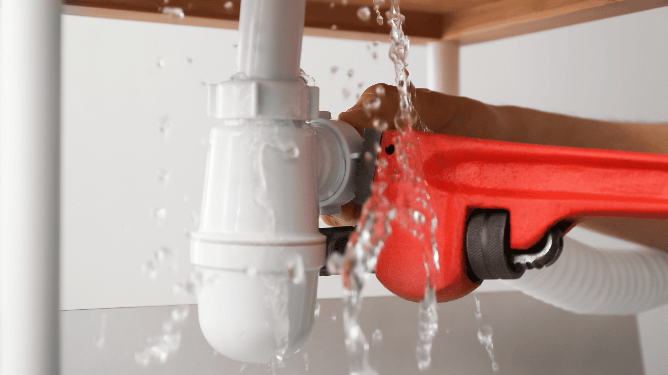 Plumber repairing a leaking pipe with a wrench during an emergency plumbing call in Champaign-Urbana, IL