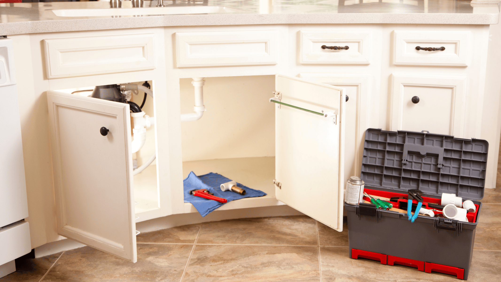 Open cabinet with plumbing pipes and a toolbox of wrenches and fittings