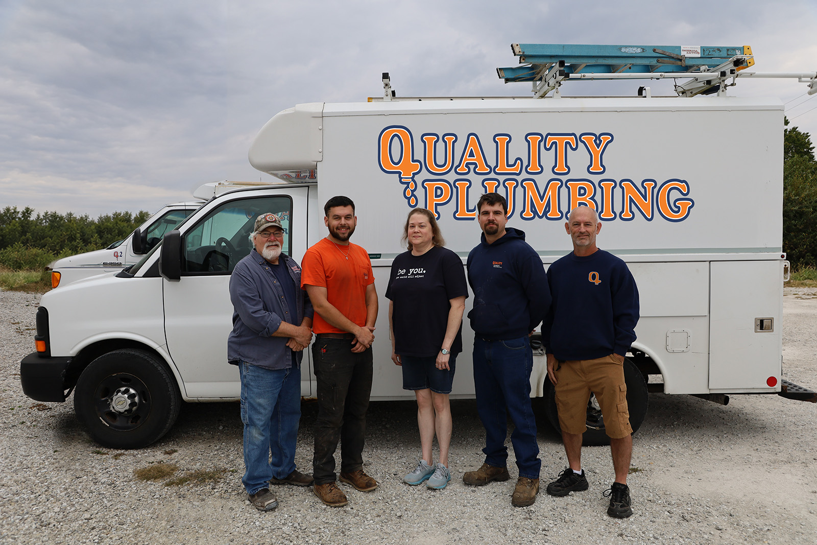 Quality Plumbing team standing in front of their service trucks